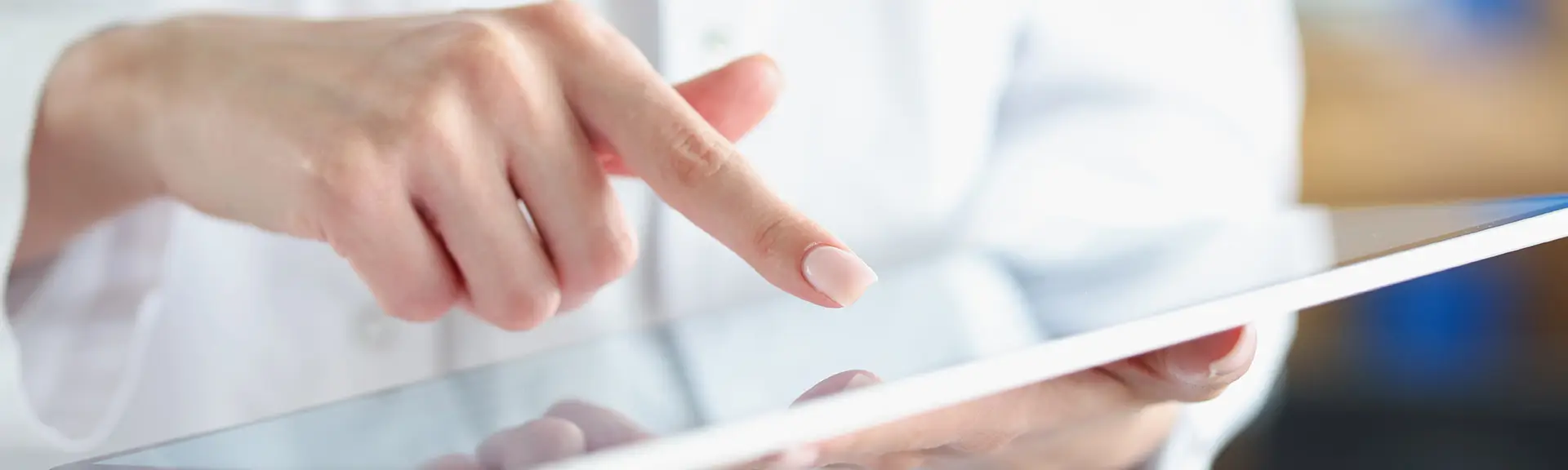 Hand einer Frau, die mit dem Zeigefinger auf ein Tablet zeigt