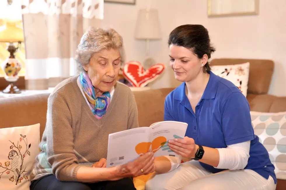 Zwei sitzende Frauen lesen gemeinsam ein Informationsheft