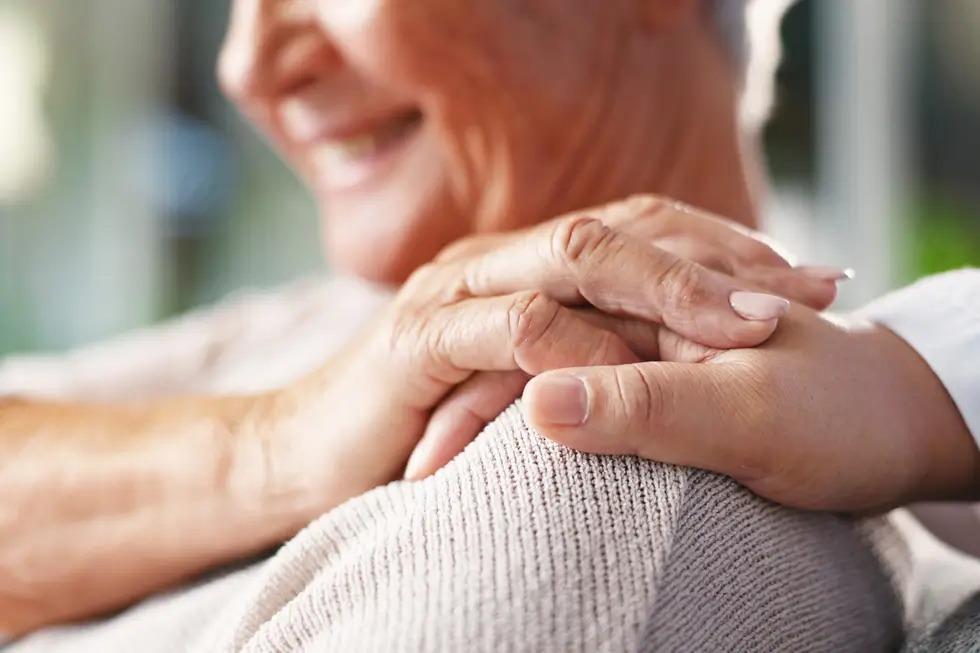 Nahaufnahme von zwei Händen, die einfühlsam auf eine Schulter gelegt sind