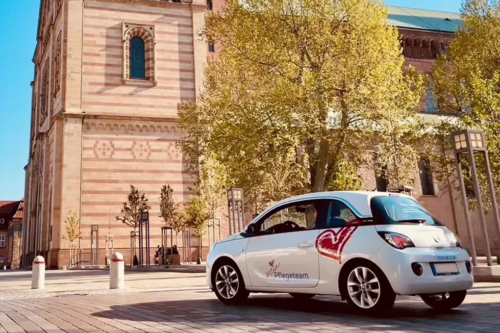 Kleiner weißer Pkw mit rotem Herzlogo steht vor dem Dom in Speyer