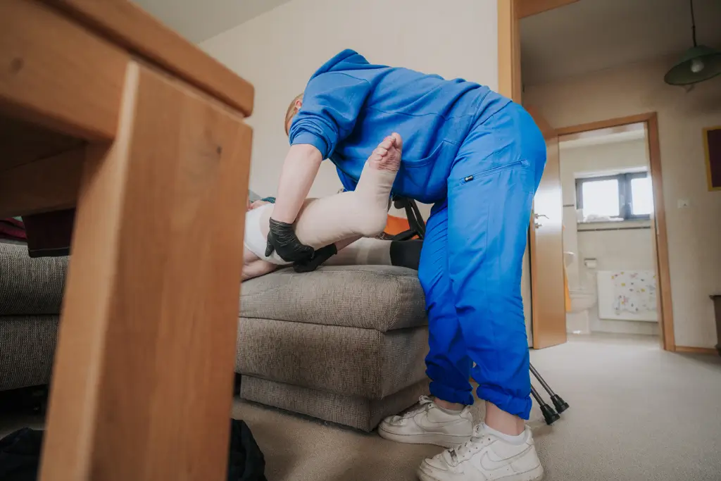 Pflegekraft versorgt einen Patienten und wechselt Verbände