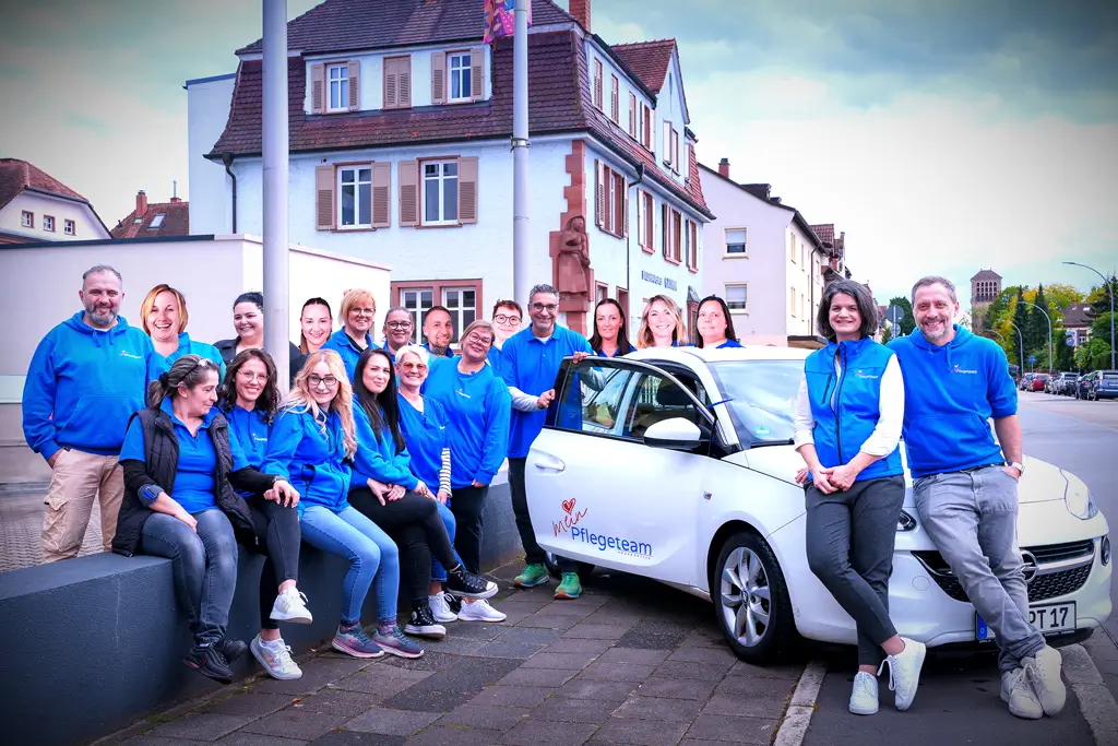 Gruppe von Menschen in blauen Jacken vor einem weißen Auto mit geöffneter Tür in einer Stadtumgebung